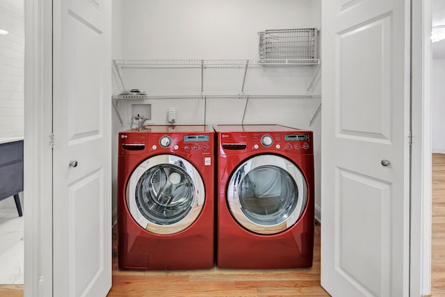 laundry room featuring washing machine and clothes dryer, wood finished floors, and laundry area