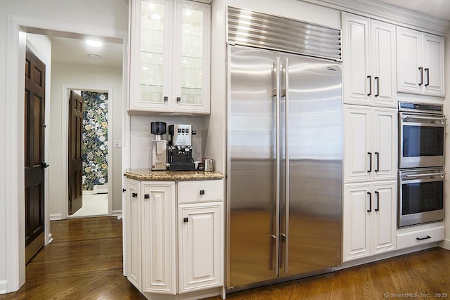 kitchen with dark wood-type flooring, glass insert cabinets, white cabinetry, and stainless steel appliances