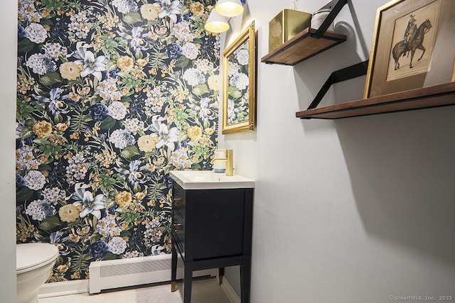 half bathroom with baseboards, vanity, and toilet