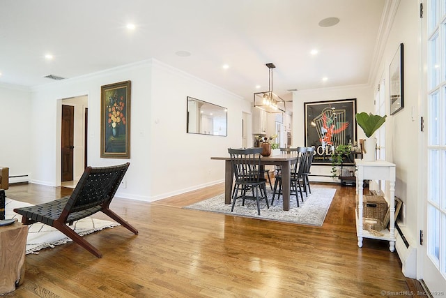 dining area featuring ornamental molding, a baseboard heating unit, wood finished floors, and visible vents
