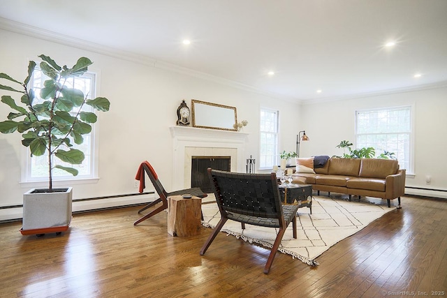 living area with crown molding, baseboard heating, wood-type flooring, and a wealth of natural light