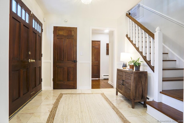 foyer featuring marble finish floor, stairs, and baseboard heating