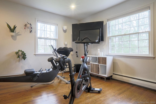 workout area with baseboard heating and wood finished floors