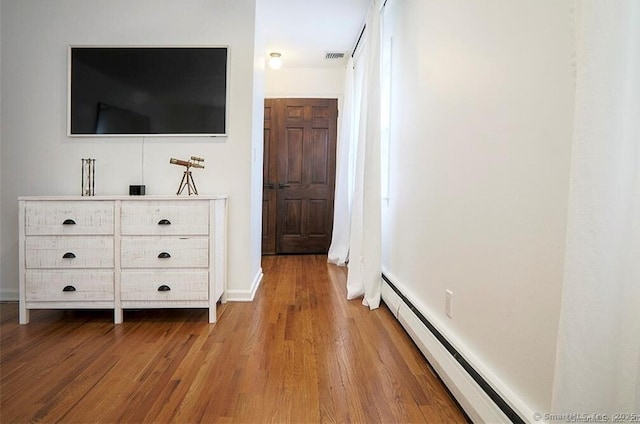 interior space with visible vents, a baseboard radiator, and wood finished floors