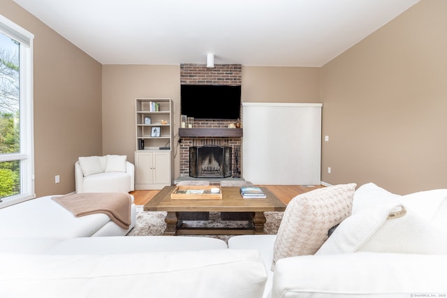 living room with a brick fireplace and wood finished floors