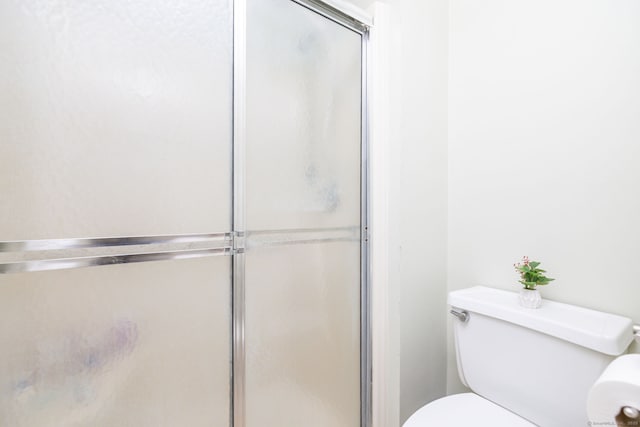 bathroom featuring toilet and a shower stall
