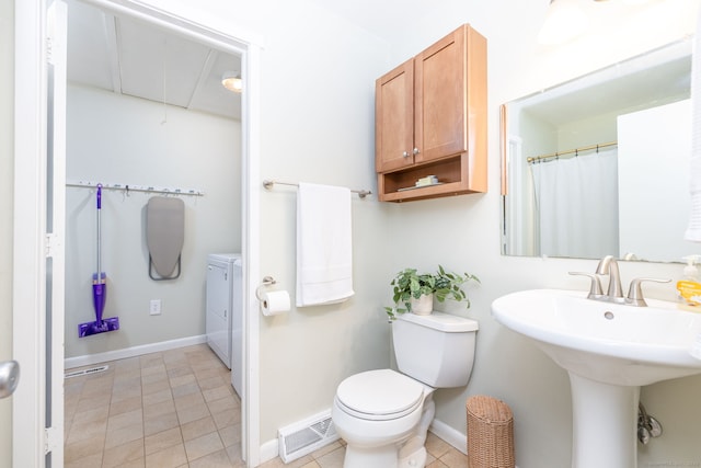 bathroom featuring visible vents, toilet, baseboards, washer and clothes dryer, and a sink