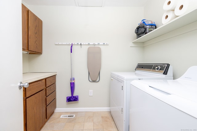 clothes washing area featuring baseboards, visible vents, cabinet space, and washer and clothes dryer
