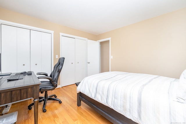 bedroom with two closets and light wood finished floors