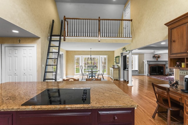 74 High St, Portland, CT 06480 - kitchen with light wood-style floors, a towering ceiling, a brick fireplace, and black electric cooktop