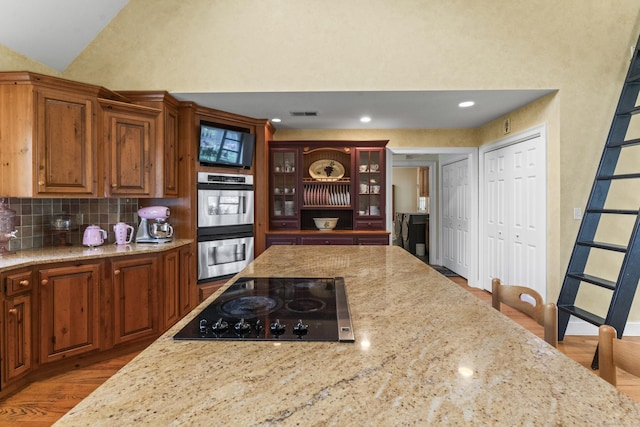74 High St, Portland, CT 06480 - kitchen with light stone counters, double oven, black electric cooktop, wood finished floors, and tasteful backsplash