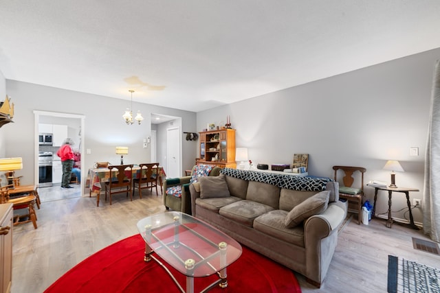 669 Heritage Vlg Unit B, Southbury, CT 06488 - living area with visible vents, light wood-type flooring, and a notable chandelier