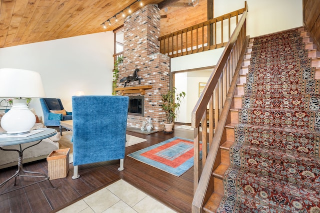sitting room with wood ceiling, rail lighting, high vaulted ceiling, and stairs
