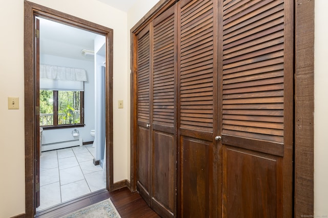 corridor featuring baseboards, a baseboard heating unit, and dark wood-type flooring