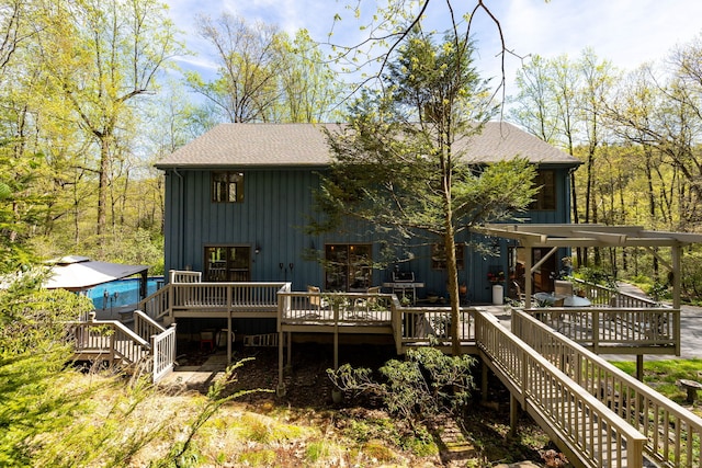 rear view of house featuring roof with shingles, a wooden deck, board and batten siding, and stairway