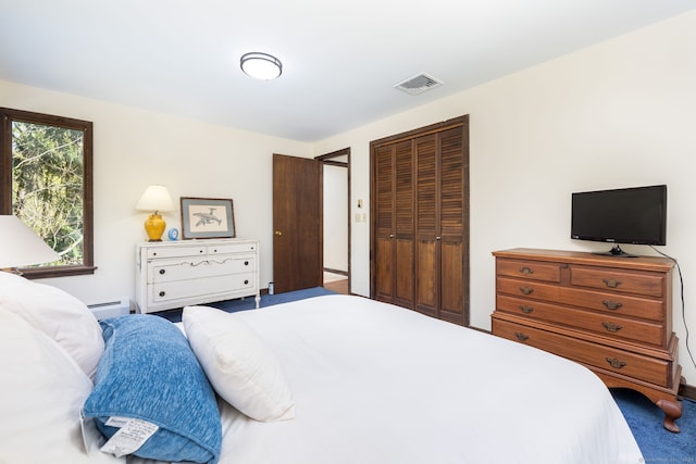 carpeted bedroom with visible vents, a baseboard heating unit, and a closet