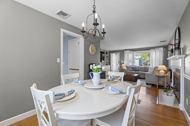 131 Vesper St, Fairfield, CT 06825 - dining space with a fireplace with flush hearth, a notable chandelier, wood finished floors, and visible vents