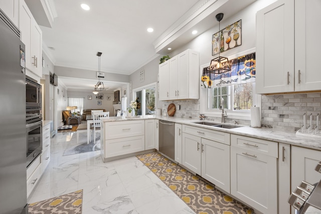 kitchen featuring a sink, stainless steel appliances, open floor plan, ornamental molding, and backsplash