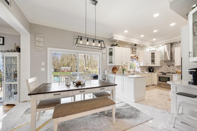 kitchen featuring ornamental molding, a sink, visible vents, stainless steel gas range, and wall chimney exhaust hood