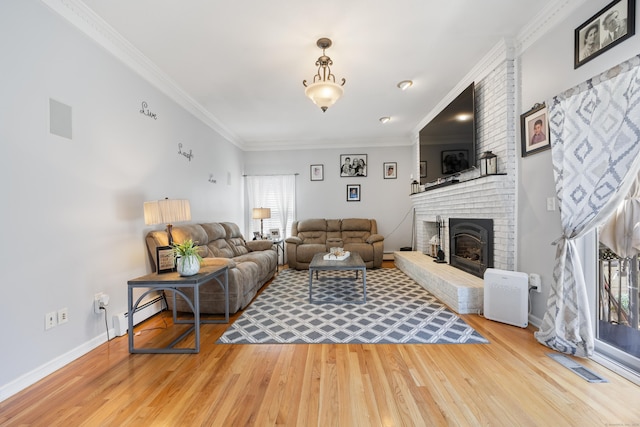 living room with light wood-style floors, a healthy amount of sunlight, crown molding, and a brick fireplace