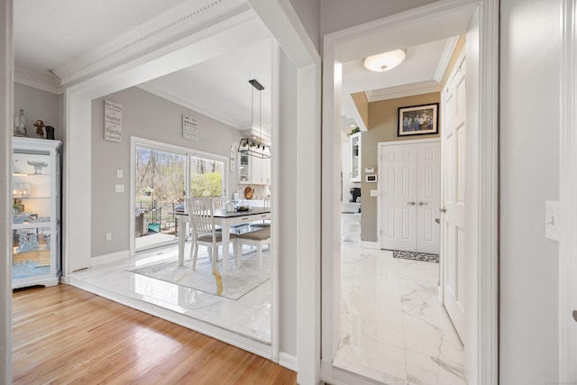 interior space with light wood-type flooring, ornamental molding, and baseboards