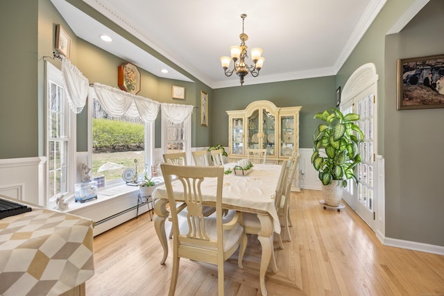 dining space featuring an inviting chandelier, plenty of natural light, light wood finished floors, and a baseboard radiator