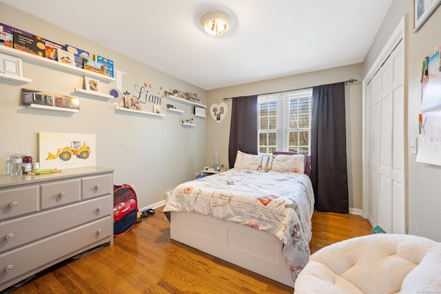 bedroom featuring baseboards, wood finished floors, and a closet