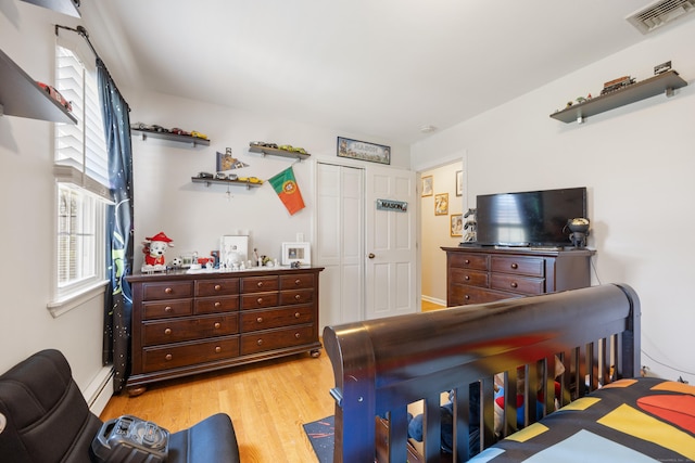 bedroom with visible vents, a baseboard heating unit, a closet, and light wood-style flooring