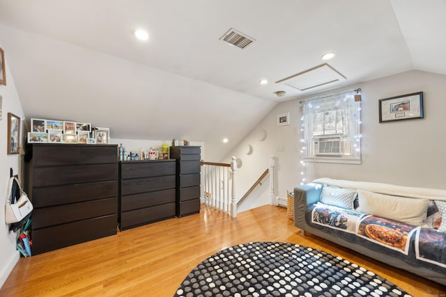 interior space featuring lofted ceiling, an upstairs landing, light wood-style floors, visible vents, and attic access