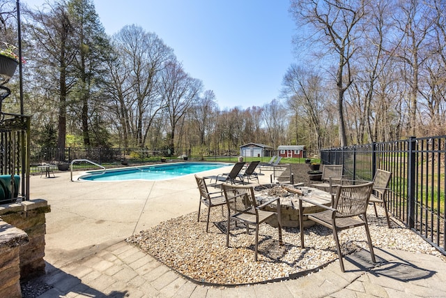 view of pool with a fire pit, fence, a storage unit, a fenced in pool, and a patio area