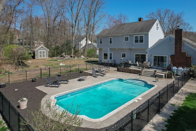 view of pool with fence, an outbuilding, a fenced in pool, a storage shed, and a patio