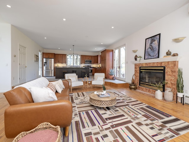 living area with an inviting chandelier, a tile fireplace, light wood-style floors, and recessed lighting