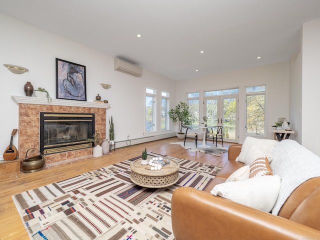 living area featuring a tiled fireplace, recessed lighting, wood finished floors, a baseboard heating unit, and a wall mounted air conditioner