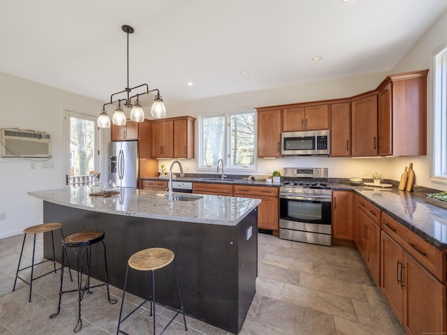 kitchen with brown cabinetry, a sink, a wall unit AC, and stainless steel appliances