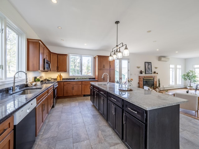 kitchen with light stone counters, stainless steel appliances, open floor plan, and a sink