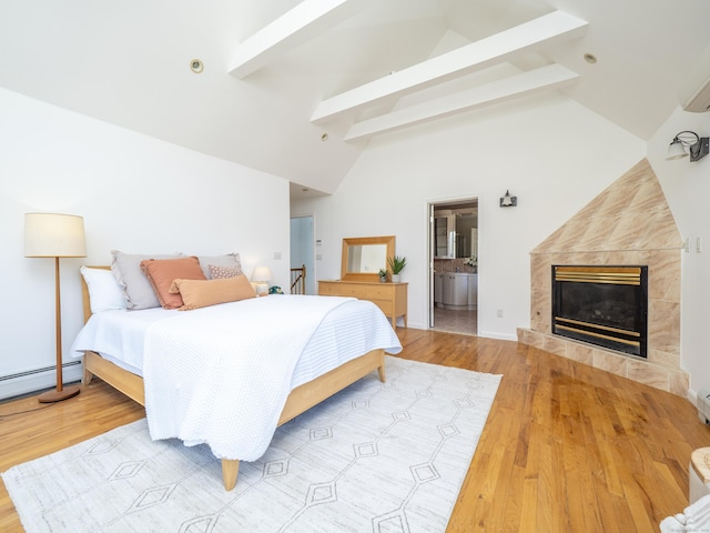 bedroom with beamed ceiling, a tile fireplace, high vaulted ceiling, baseboard heating, and wood finished floors