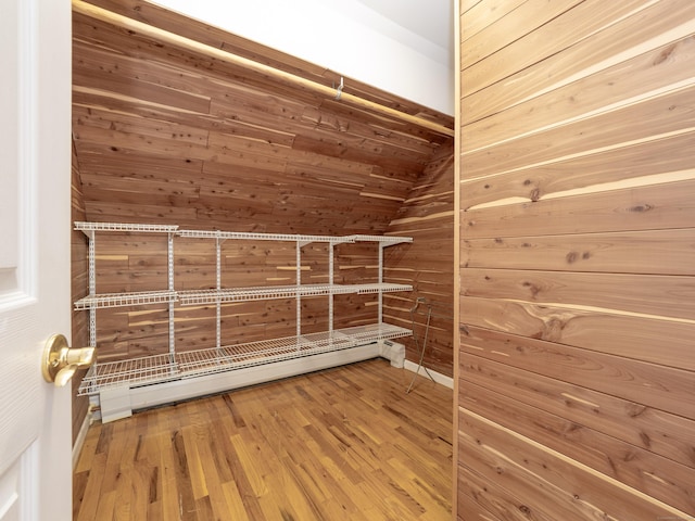 spacious closet featuring lofted ceiling, wood finished floors, and baseboard heating