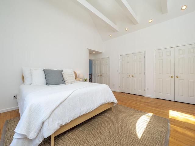 bedroom featuring light wood-style floors, multiple closets, recessed lighting, and high vaulted ceiling