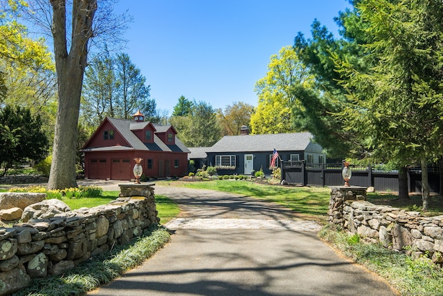 view of front of house featuring fence, a chimney, and aphalt driveway