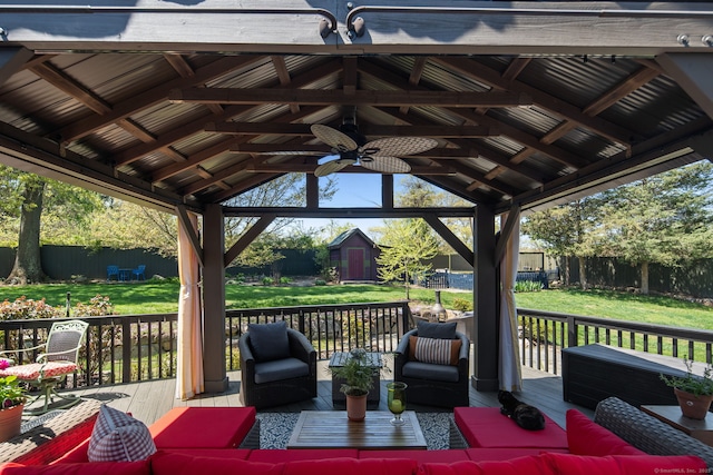 wooden deck with a gazebo, outdoor lounge area, a fenced backyard, a lawn, and a ceiling fan