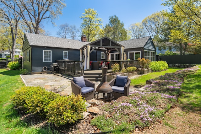 rear view of house with fence, a deck, a patio, a chimney, and a gazebo
