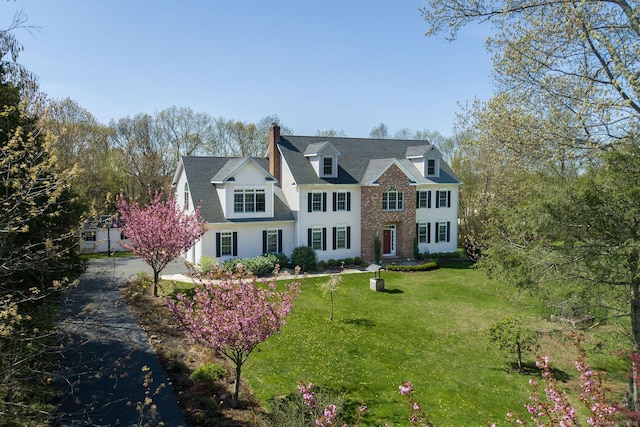 view of front of property featuring a chimney, a front lawn, and brick siding
