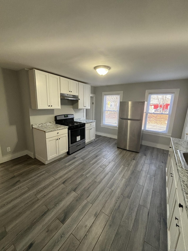 kitchen featuring white cabinets, stainless steel appliances, baseboards, under cabinet range hood, and dark wood finished floors