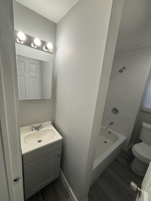 bathroom featuring toilet, vanity, washtub / shower combination, and wood finished floors