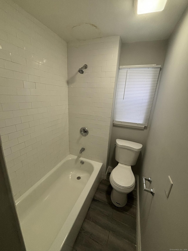 bathroom with wood finished floors, toilet, and shower / bathtub combination