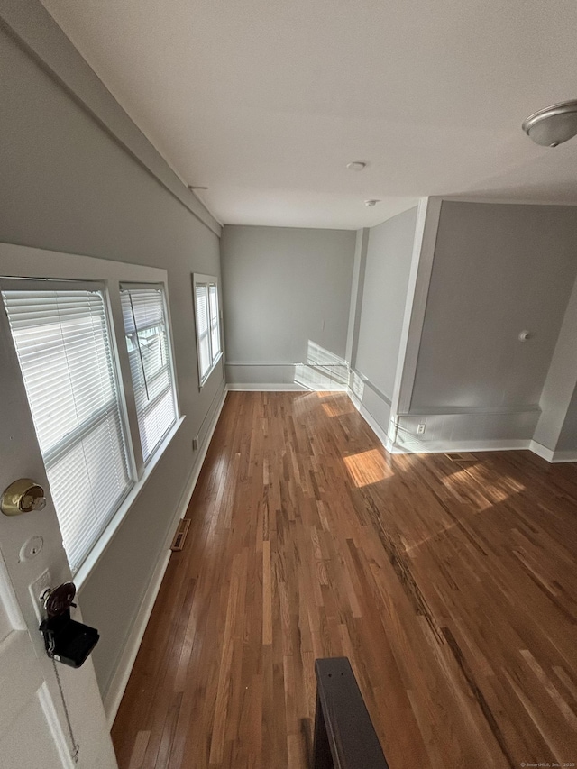 unfurnished room featuring visible vents, wood finished floors, and baseboards