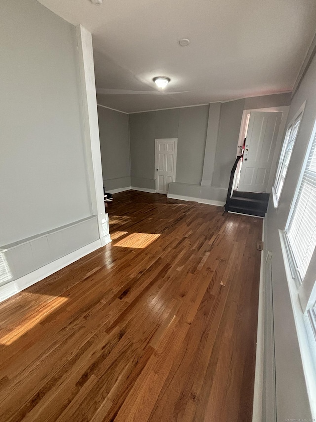 spare room with baseboards and dark wood-type flooring