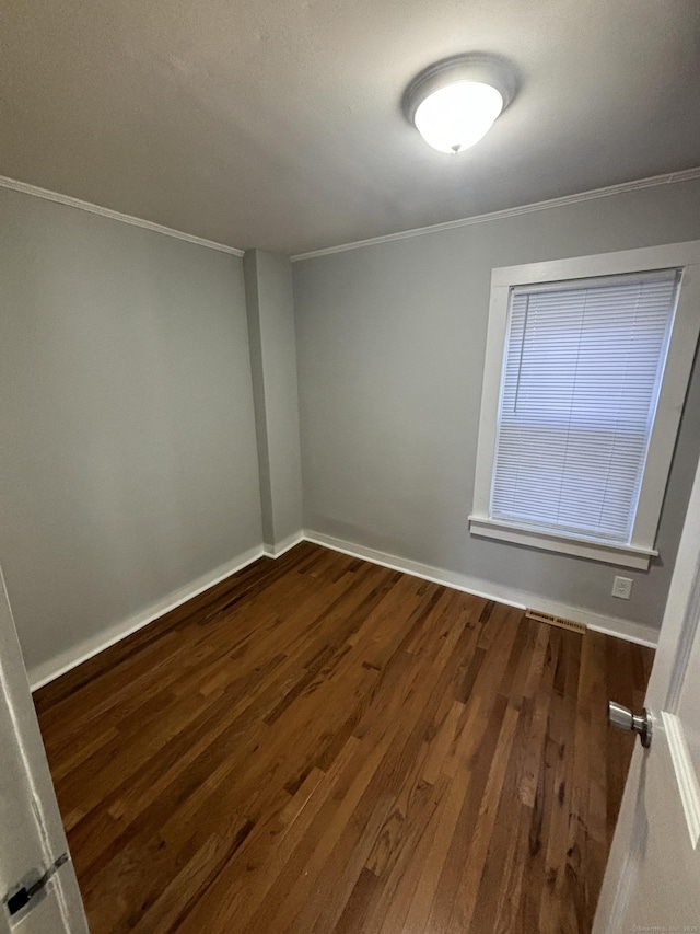 unfurnished room featuring baseboards, visible vents, ornamental molding, and dark wood-style flooring