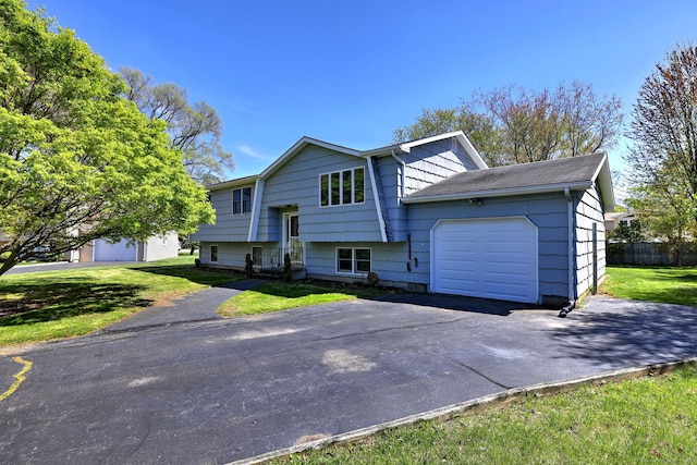 bi-level home featuring a garage, fence, driveway, and a front yard