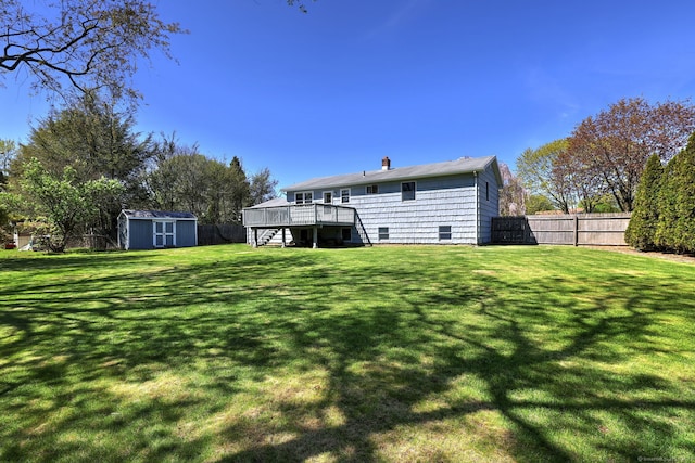 back of house with a storage shed, a deck, stairway, a fenced backyard, and a chimney